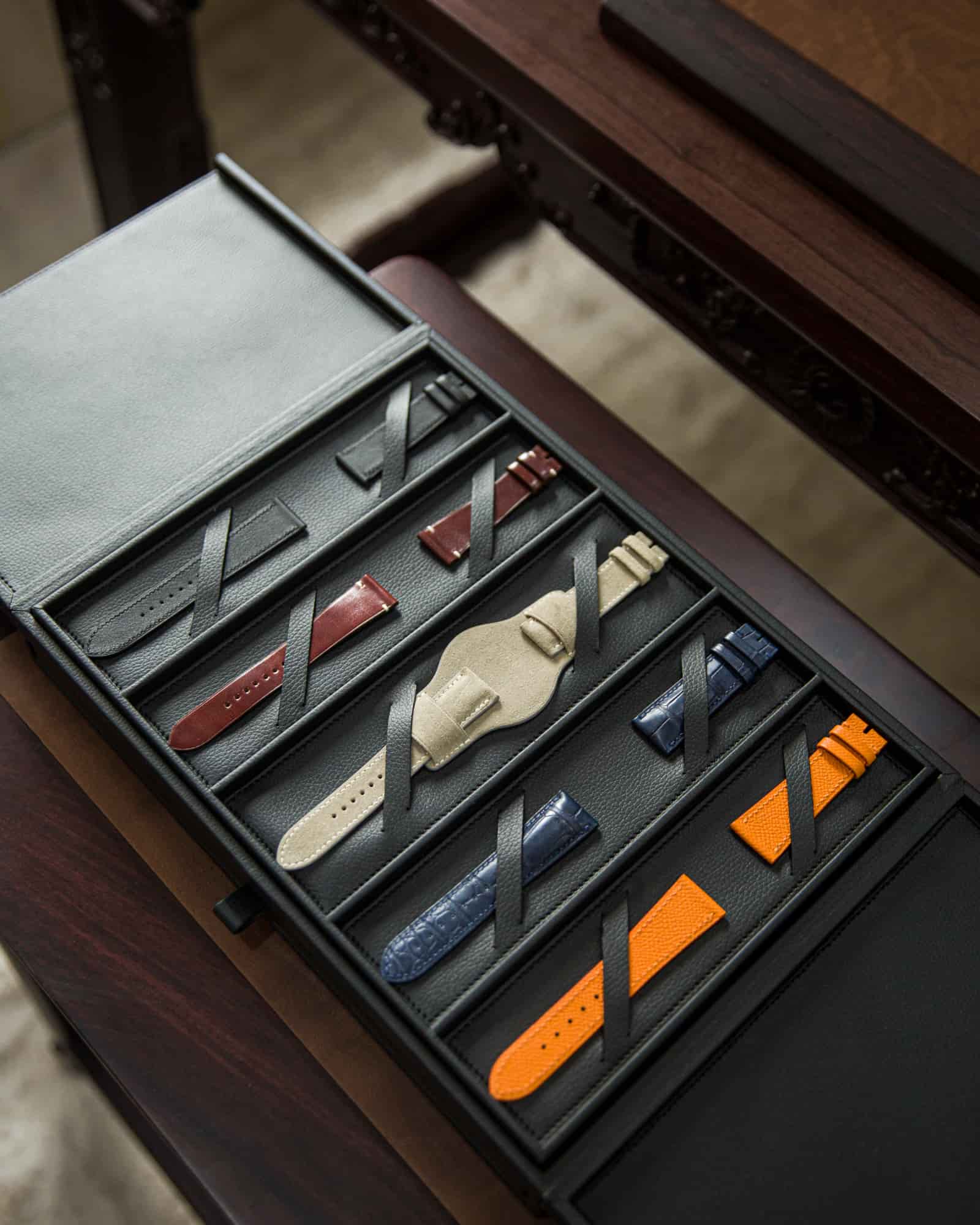 Bespoke leather sample folio open on the workbench, showing rows of strap samples a client selects from, at AKC