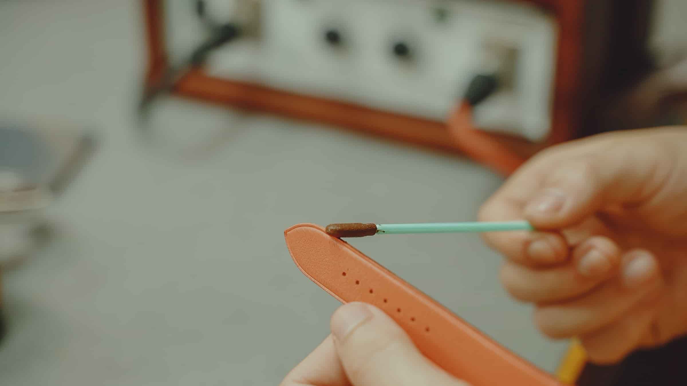 Edge paint being laid onto the finished edge of a leather watch strap with an applicator at AKC